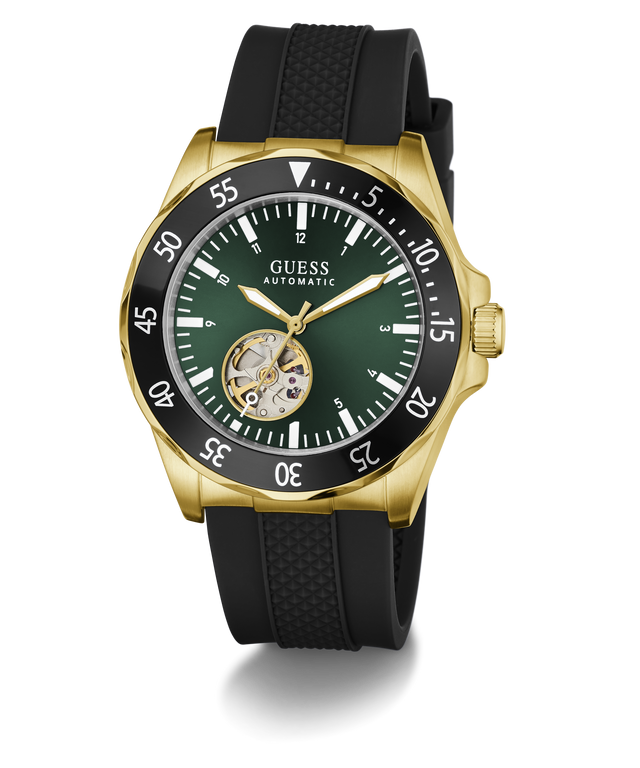 A GUESS Automatic watch with a gold-tone case, black textured strap, and a dark green dial featuring a skeletonized sub-dial showing the inner movement.