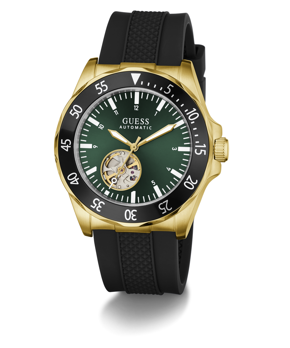 A GUESS Automatic watch with a gold-tone case, black textured strap, and a dark green dial featuring a skeletonized sub-dial showing the inner movement.