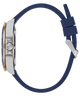 Side profile of a wristwatch with a navy blue silicone strap, a brushed silver-tone case, and a small rose gold accent on the bezel, shown on a plain white background.
