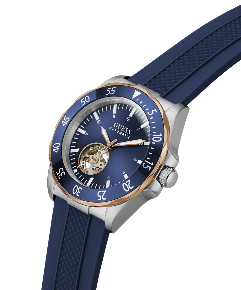 A Guess Automatic watch with a dark blue dial, a blue textured rubber strap, a stainless steel case, and a rose gold bezel. lifestyle