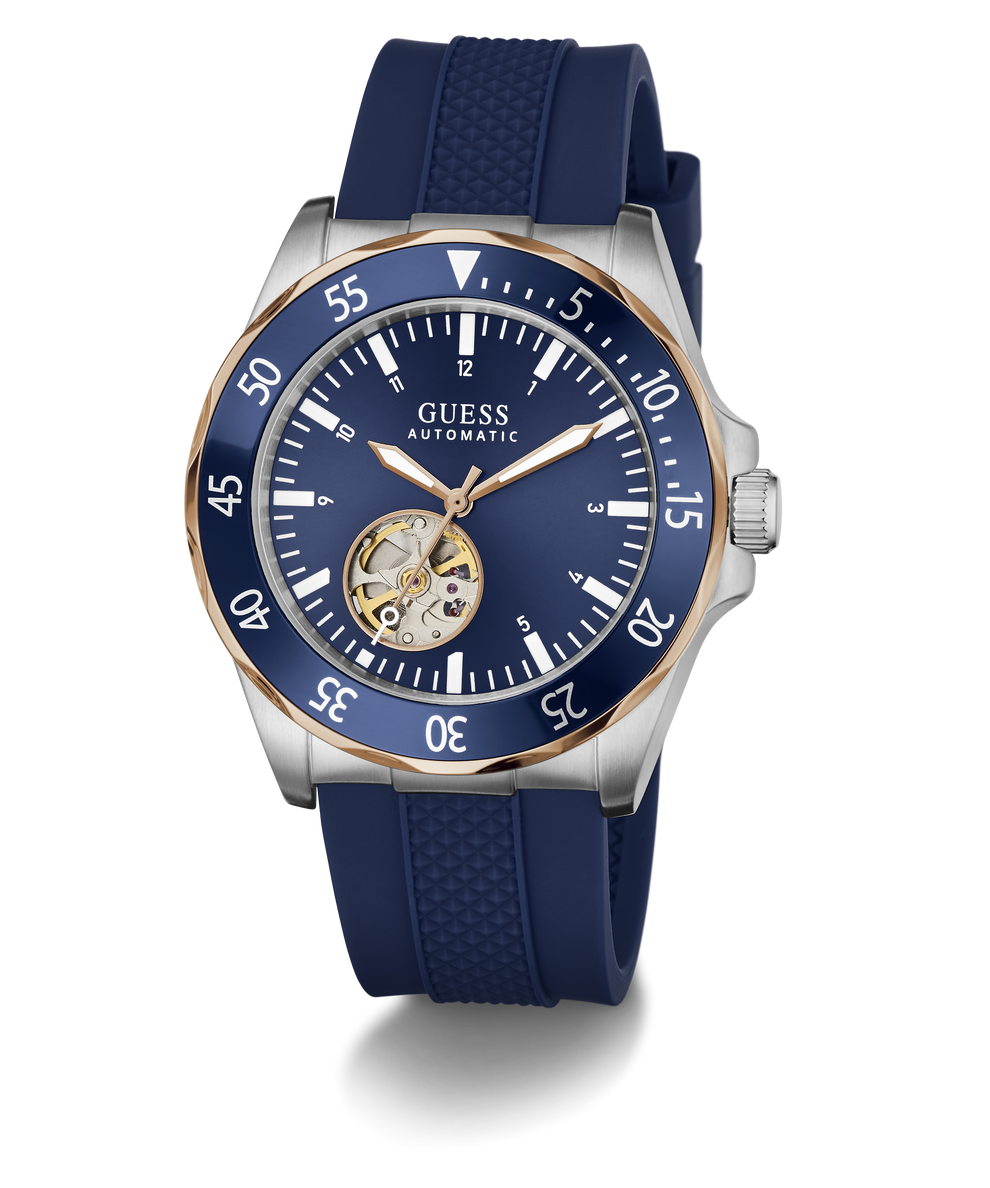 A GUESS Automatic watch with a blue dial, blue textured silicone strap, and a silver-tone stainless steel case accented with a gold-tone case bezel and skeletonized inner dial.