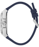 Close-up side view of a watch with a silver-toned metal case and a dark navy blue silicone strap on a plain white background.