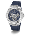 A GUESS men's watch featuring a silver stainless steel case, a blue dial with three subdials, and a dark blue silicone strap, shown on a clean white background.