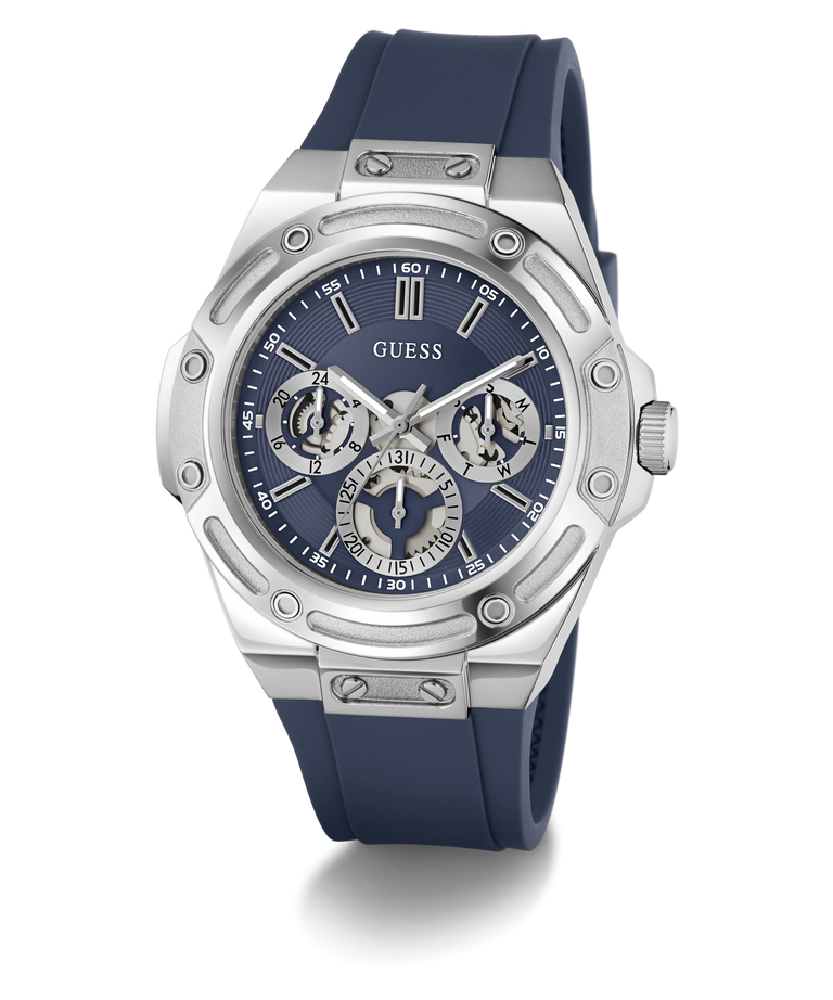 A GUESS men's watch featuring a silver stainless steel case, a blue dial with three subdials, and a dark blue silicone strap, shown on a clean white background.