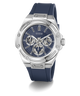 A GUESS men's watch featuring a silver stainless steel case, a blue dial with three subdials, and a dark blue silicone strap, shown on a clean white background.