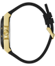 A close-up side profile of a watch with a gold-tone geometric case and a black silicone strap, shown on a plain white background.