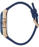 A close-up side profile of a watch with a navy blue strap and a gold-toned case, set against a solid white background.