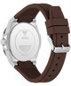 A close-up of a wristwatch shown from the back, featuring a silver stainless steel case and a dark brown silicone strap with a silver buckle.