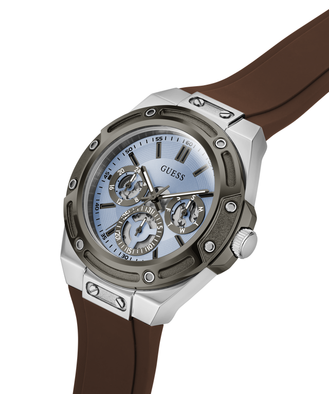 A GUESS men's watch featuring a silver-toned stainless steel case, a light blue dial with skeletonized subdials, and a brown rubber strap, shown on a clean white background. lifestyle