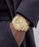 A gold-tone GUESS chronograph watch with a diamond-encrusted bezel and matching bracelet, shown worn on a person's wrist.