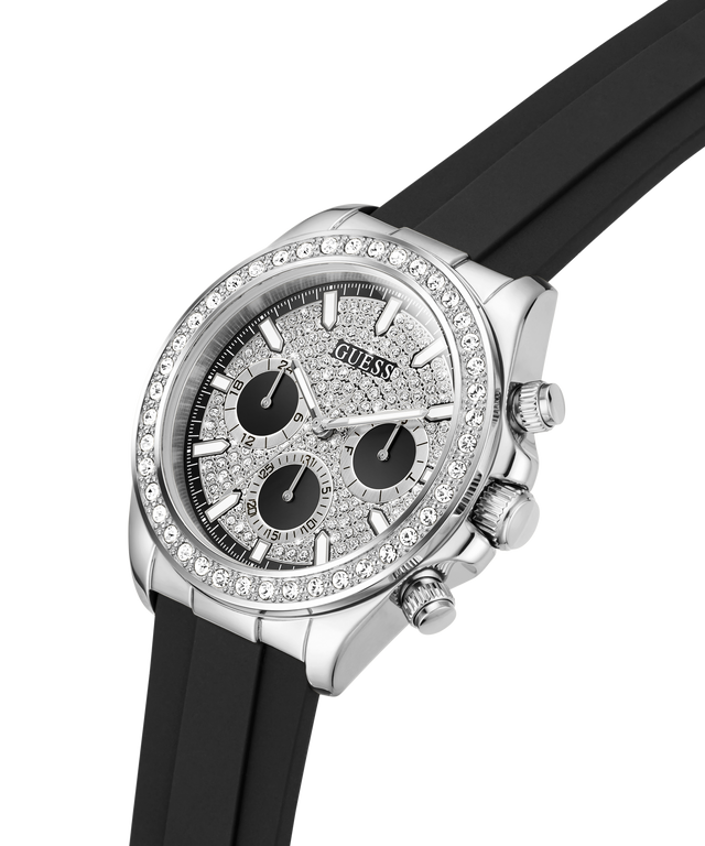 A Guess wristwatch with a silver-tone case, crystal-encrusted bezel, textured silver dial with three black subdials, and a black rubber strap, shown on a white background. lifestyle