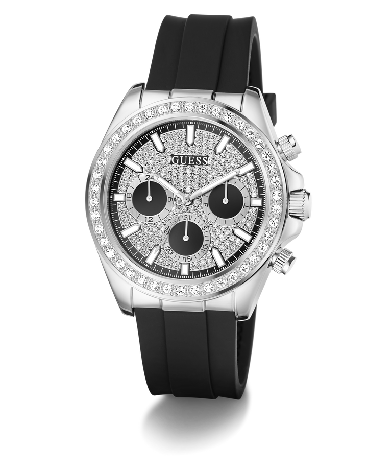 A Guess wristwatch with a silver-tone case, a bezel set with clear stones, a textured black dial with three black subdials, and a black silicone strap, shown on a white background.