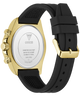 Back view of a Guess watch with a gold-tone case and a black silicone strap, showing the branded back plate and crown details.