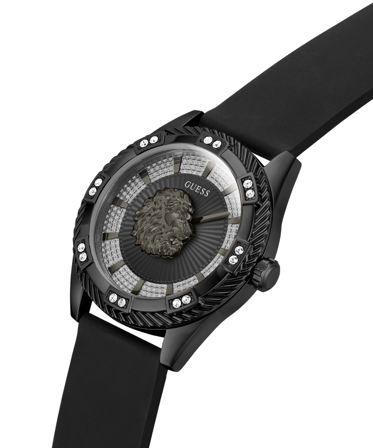A luxury wristwatch by Guess featuring a black rubber strap, a textured black bezel adorned with small clear crystals, and a unique sunburst dial with a central lion head medallion. lifestyle