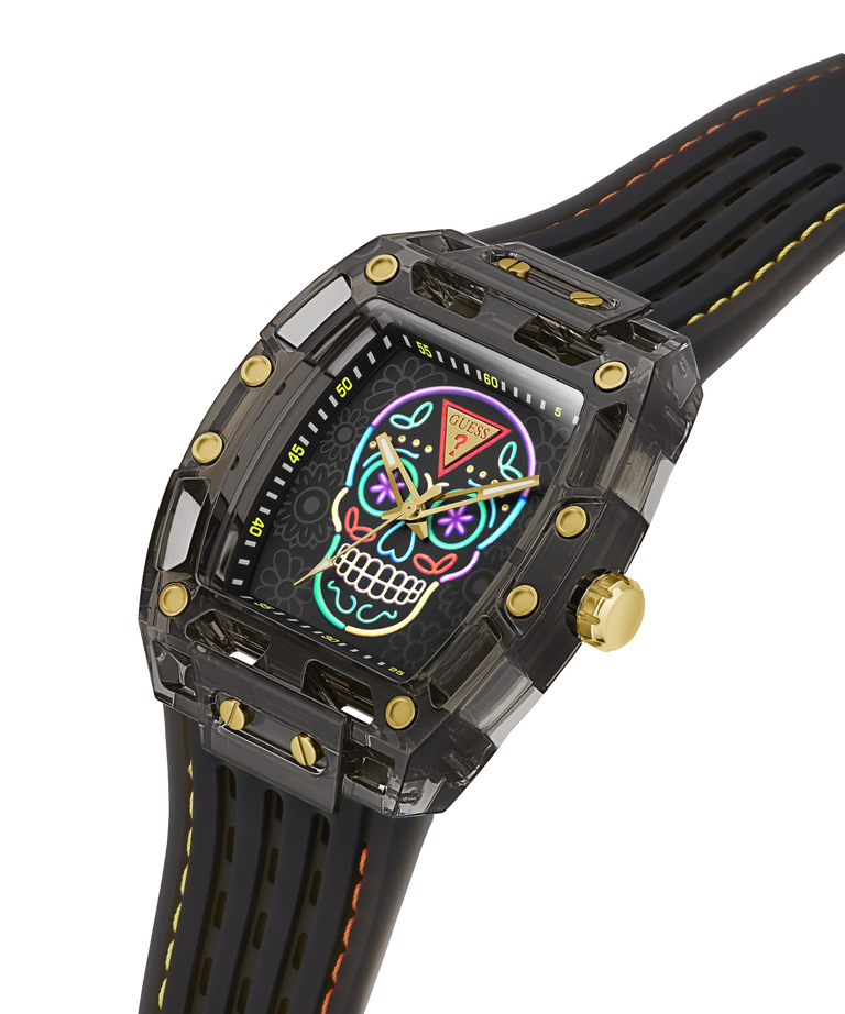 A luxury watch with a transparent black case, gold-tone screws and crown, and a black strap with orange stitching. The dial features a vibrant, colorful sugar skull graphic. lifestyle
