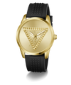 A Guess women's analog watch featuring a gold-tone round case, a gold-tone dial with an embossed triangle logo, and a textured black silicone strap.