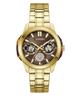 A gold-tone stainless steel wrist watch with a brown dial, featuring three sub-dials, gold-tone hour markers, and a matching gold-tone link bracelet. The brand name 'GUESS' is clearly visible on the dial.