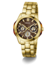 Gold-tone stainless steel wristwatch with a brown dial, featuring three subdials, gold-tone hour markers, and a matching gold-tone link bracelet. The GUESS brand name is visible on the dial.