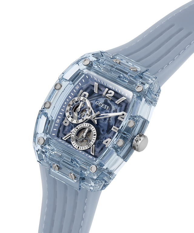 A GUESS wristwatch with a transparent light blue case and matching silicone strap, featuring a blue skeleton dial with silver-tone subdials and markers. lifestyle