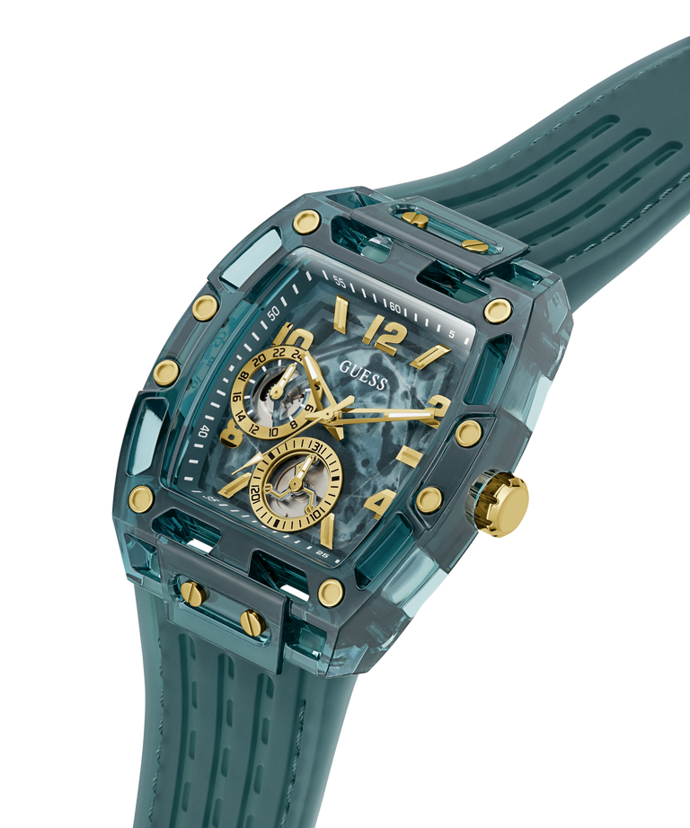 A GUESS wristwatch with a translucent teal resin case, matching strap, gold-tone accents, and a skeleton dial showing the inner movement, photographed on a clean white background. lifestyle