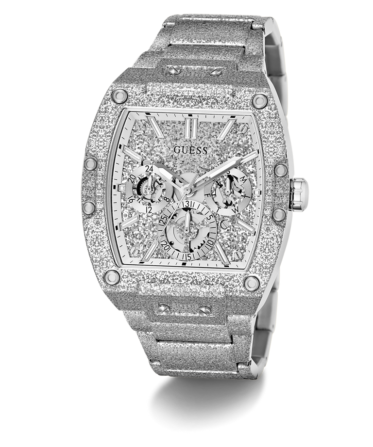 A luxury Guess wristwatch with a silver-tone metal case and bracelet, heavily embellished with sparkling clear crystals. The dial is a complex multi-dial skeleton design with matching crystal details, featuring the GUESS brand name at the top.