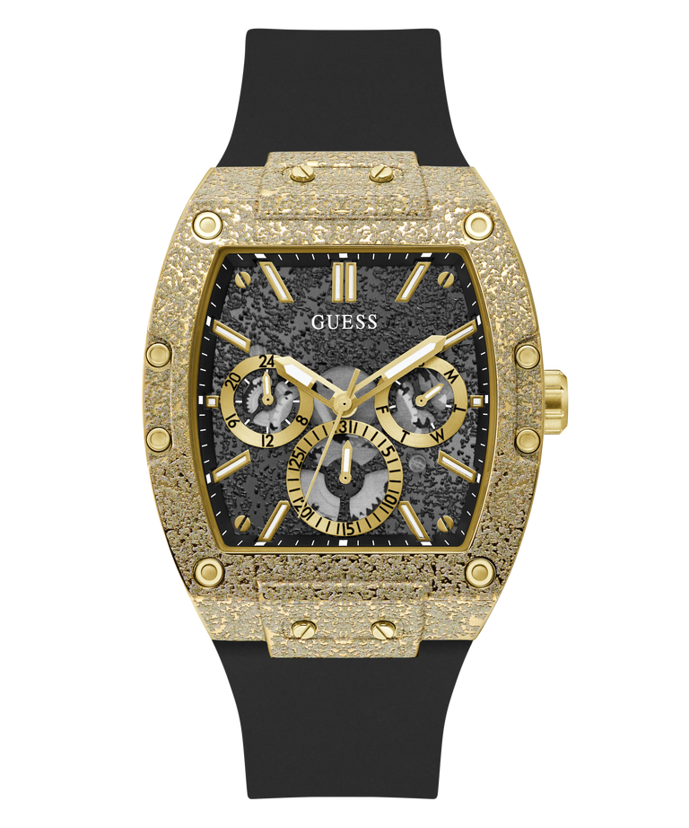 A luxury wristwatch by Guess featuring an ornate gold-tone case with a textured bezel, a black multi-dial dial, and a black rubber strap, shown against a plain white background.