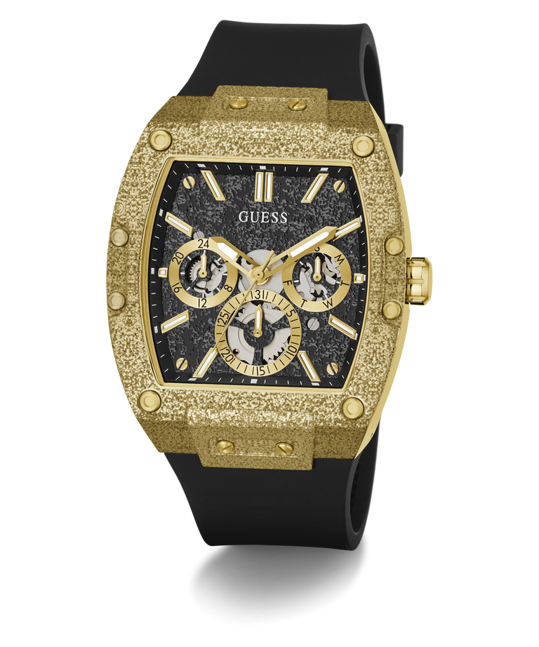 A luxury wristwatch by Guess featuring a textured gold-tone case, a black dial with three subdials, and a black rubber strap, shown on a clean white background.