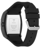 The back of a GUESS watch with a black case and a black silicone strap, featuring a silver-toned buckle and a silver metal case back with printed specifications.