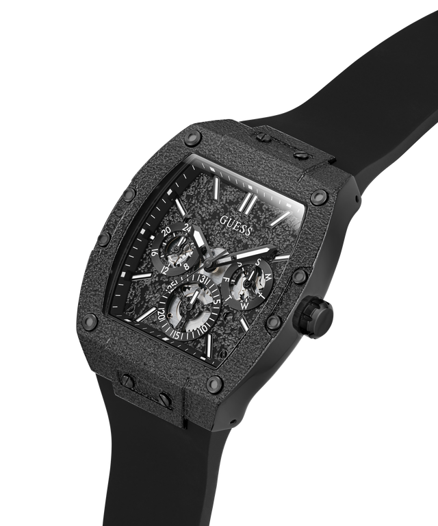 A GUESS men's watch featuring a rugged, textured black case and a matching black strap, with a detailed skeleton-style dial and Roman numeral hour markers, shown on a plain white background. lifestyle