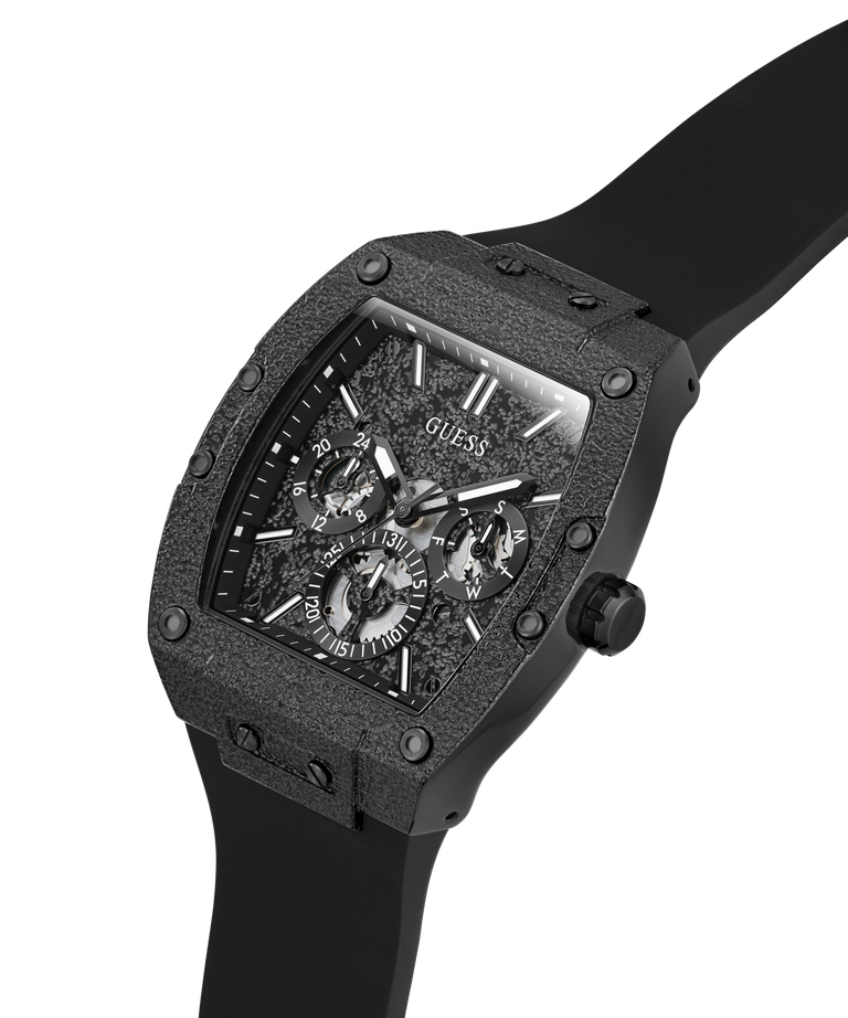 A GUESS men's watch featuring a rugged, textured black case and a matching black strap, with a detailed skeleton-style dial and Roman numeral hour markers, shown on a plain white background. lifestyle
