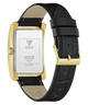 A GUESS wristwatch shown from the back, featuring a rectangular gold-tone case, a black textured leather strap, and a silver-toned backplate with brand text.