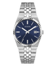 A GUESS men's analog watch with a stainless steel link bracelet, a fluted bezel, and a deep blue dial with silver-tone hands and markers.