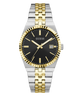 A GUESS men's analog watch with a two-tone silver and gold stainless steel bracelet, a gold fluted bezel, and a black dial with gold hands and markers.