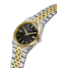 A GUESS men's two-tone watch with a black dial, gold-tone hands and markers, and a silver and gold-tone stainless steel link bracelet, shown on a clean white background. lifestyle