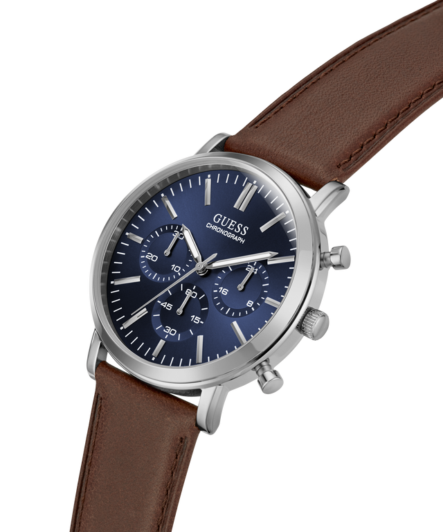 A GUESS chronograph watch with a silver-tone stainless steel case, a dark blue dial with three subdials, and a brown leather strap, shown on a plain white background. lifestyle