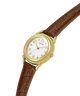 A vintage Guess wristwatch with a gold-tone case, white dial, and brown leather strap, shown diagonally on a plain white background. lifestyle