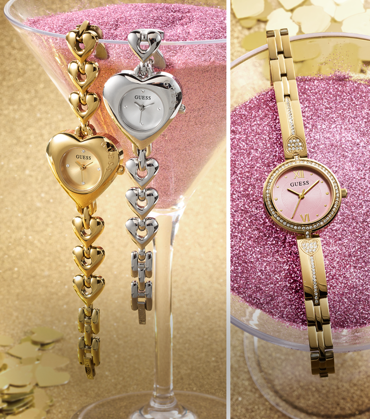 Two heart watches draped obver a martini glass and a gold watch with a pink face sitting on pink sand