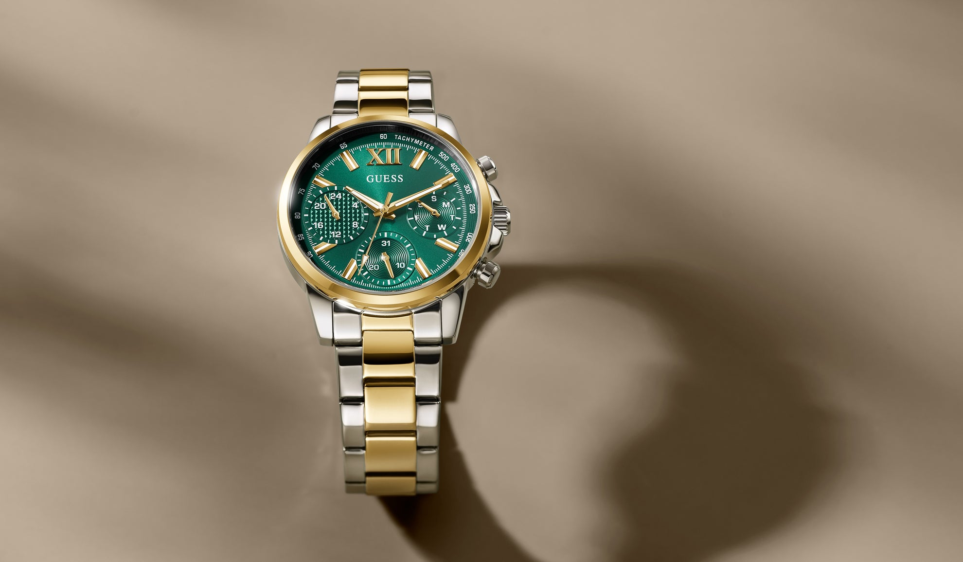 GW0933L2 watch with green face and gold and silver band on a beige background