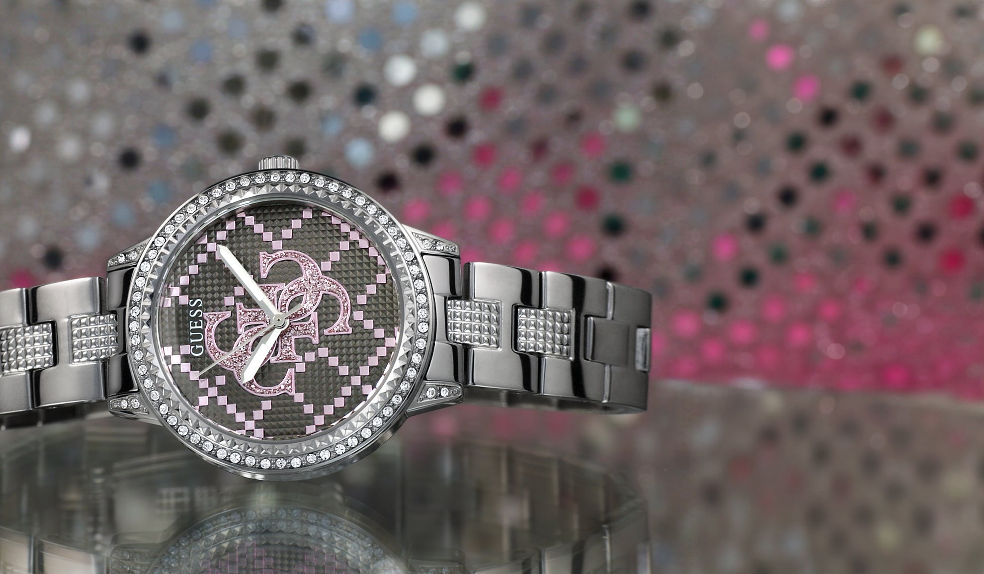 silver watch with stones on bezel and quattro G logo on dial outlined in pink