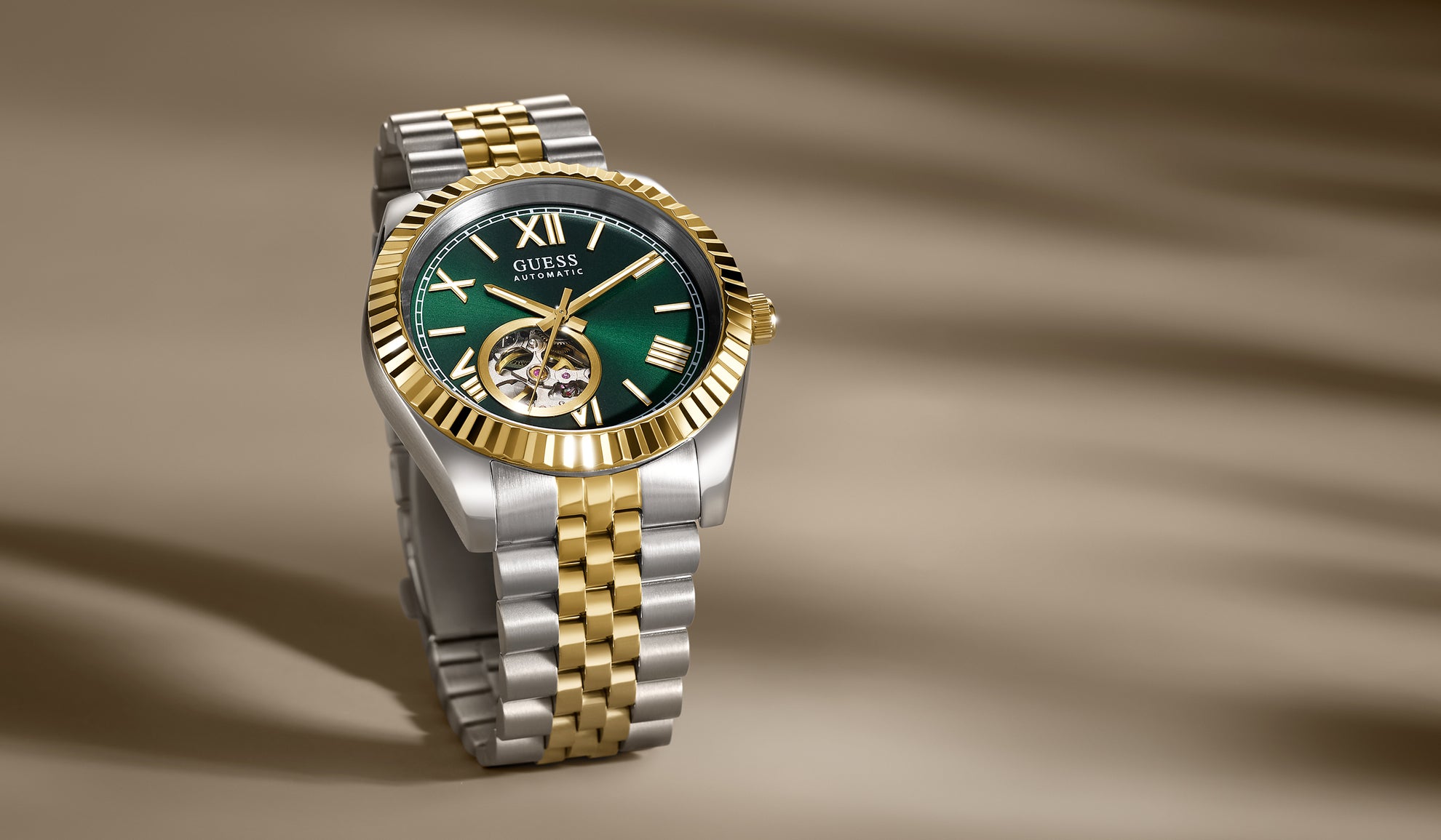 Two-tone automatic watch with green face on a brown background