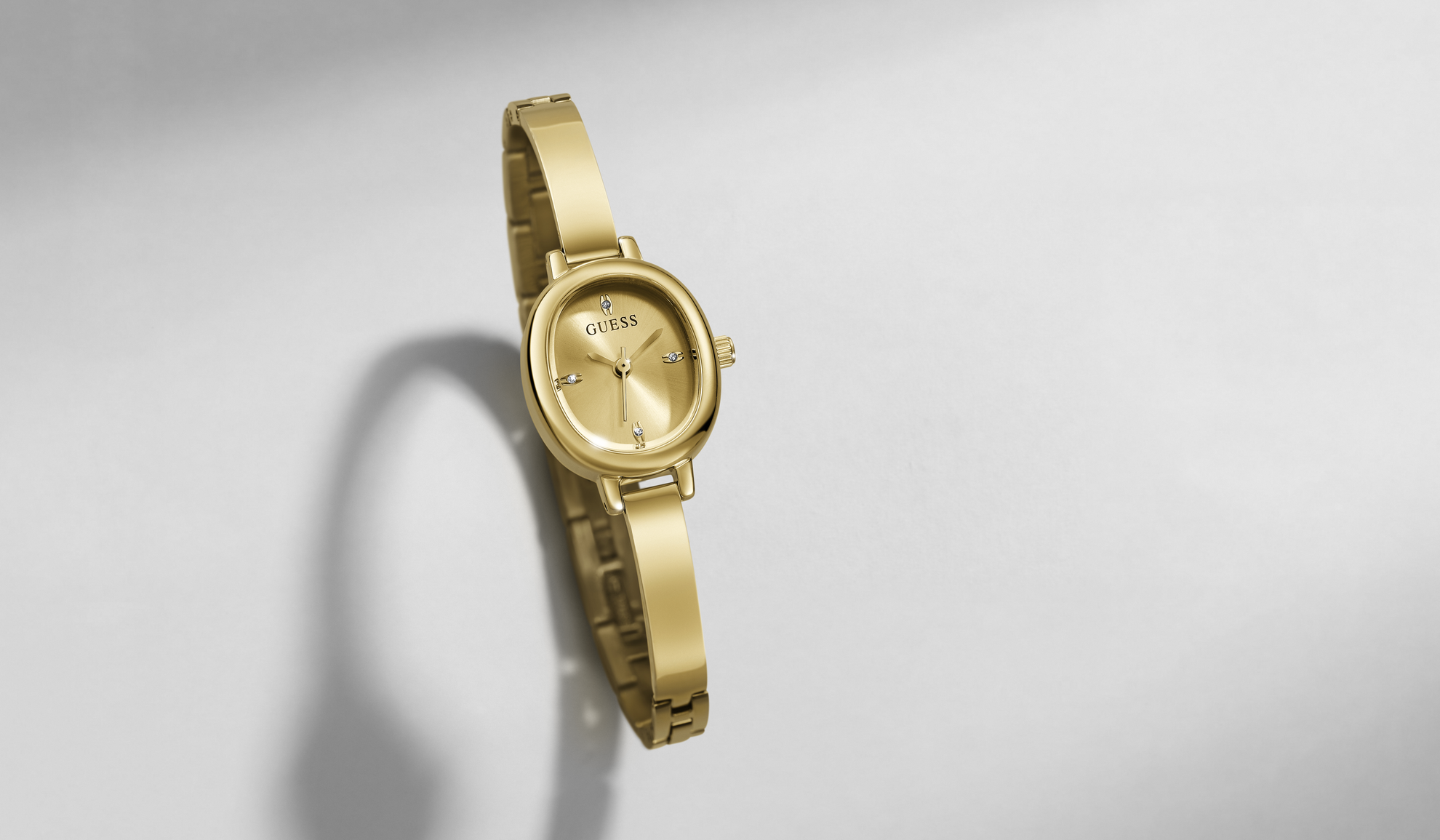 A gold-tone women's watch with a slim oval case and matching link bracelet, shown floating against a light gray background with a soft shadow.