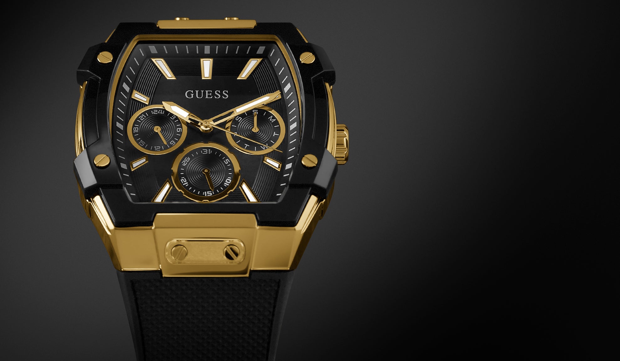 Gold and black Guess watch on a dark background