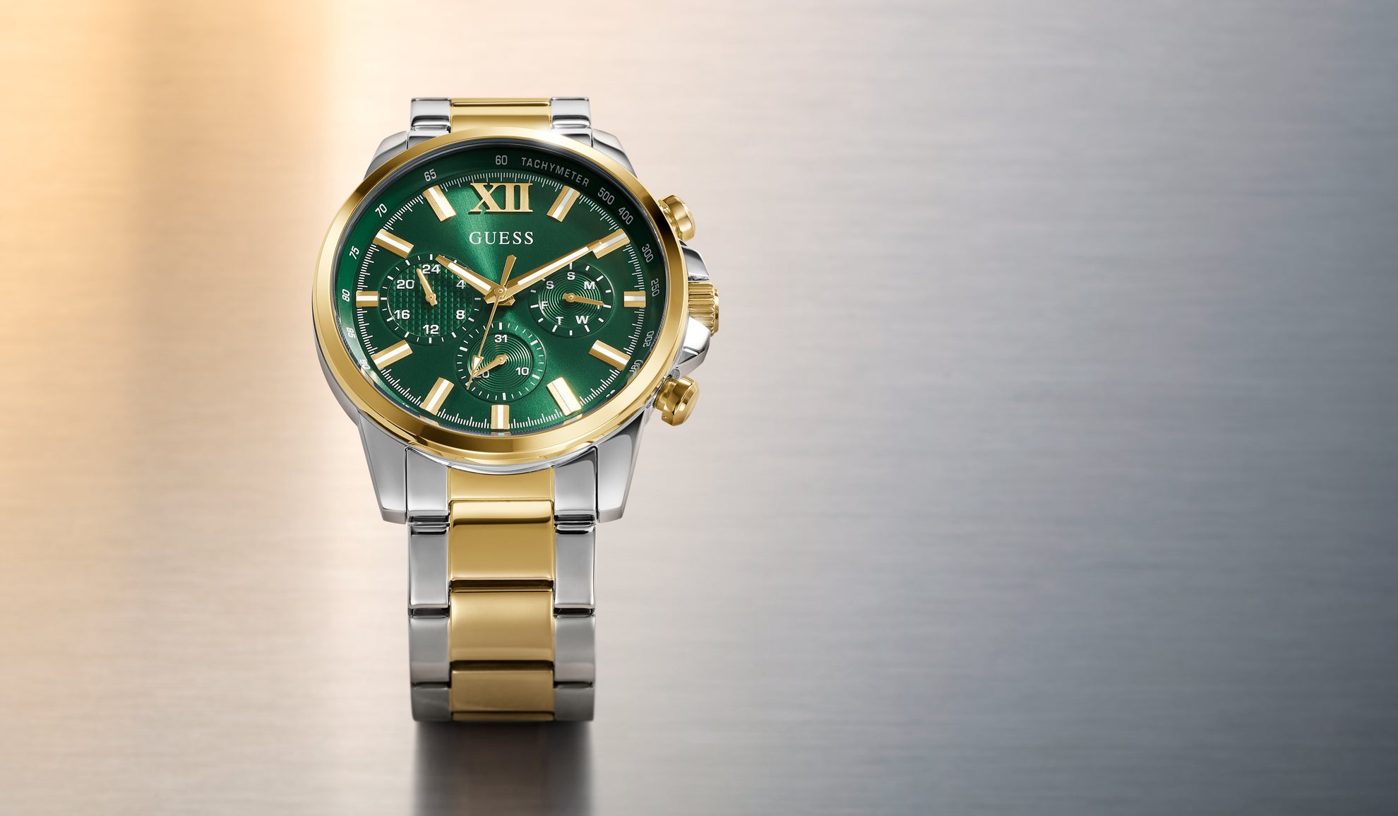 Gold and silver watch with green face on a gradient background