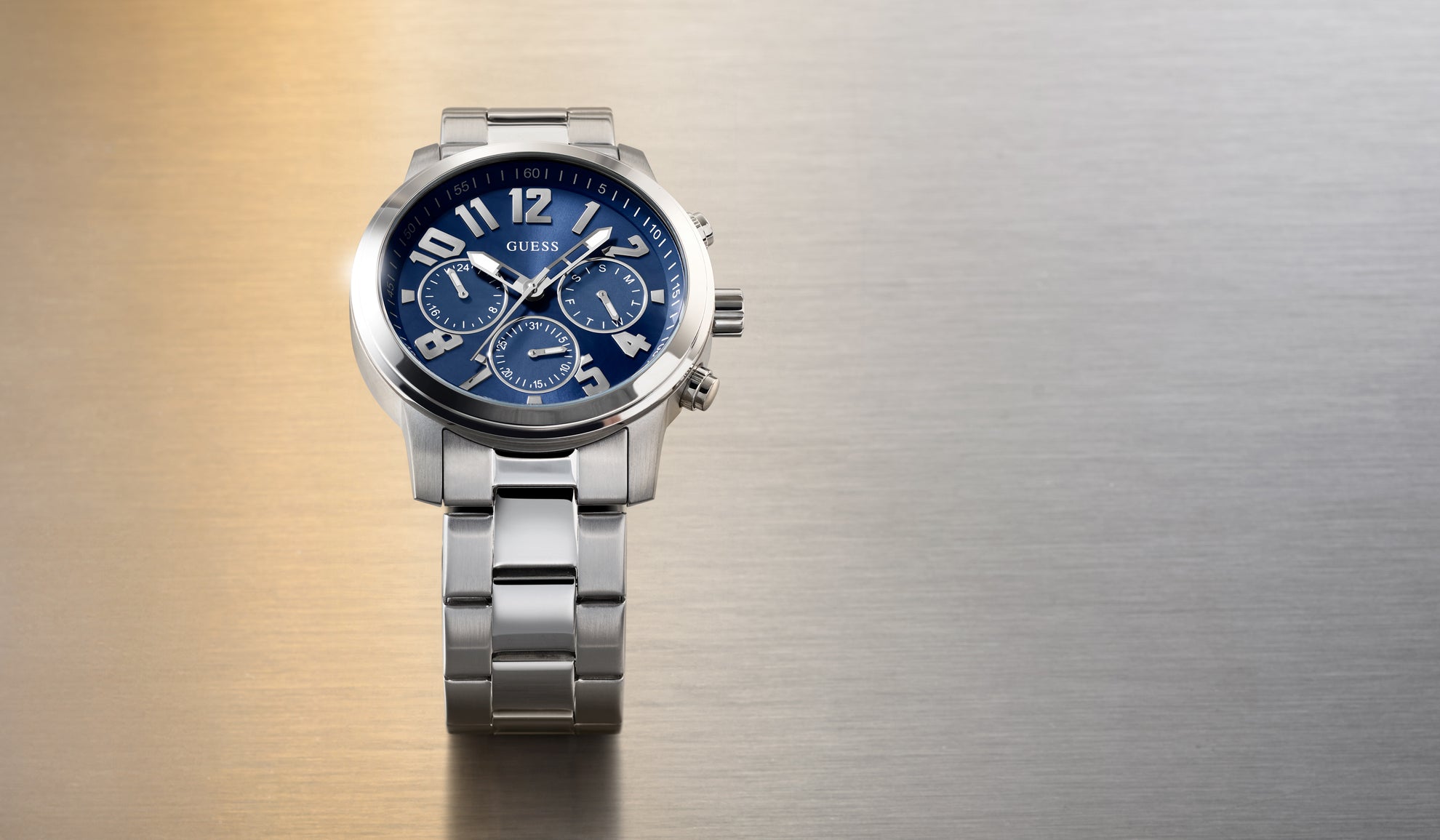 Silver watch with a blue face on a textured gold and silver background GW1006G1