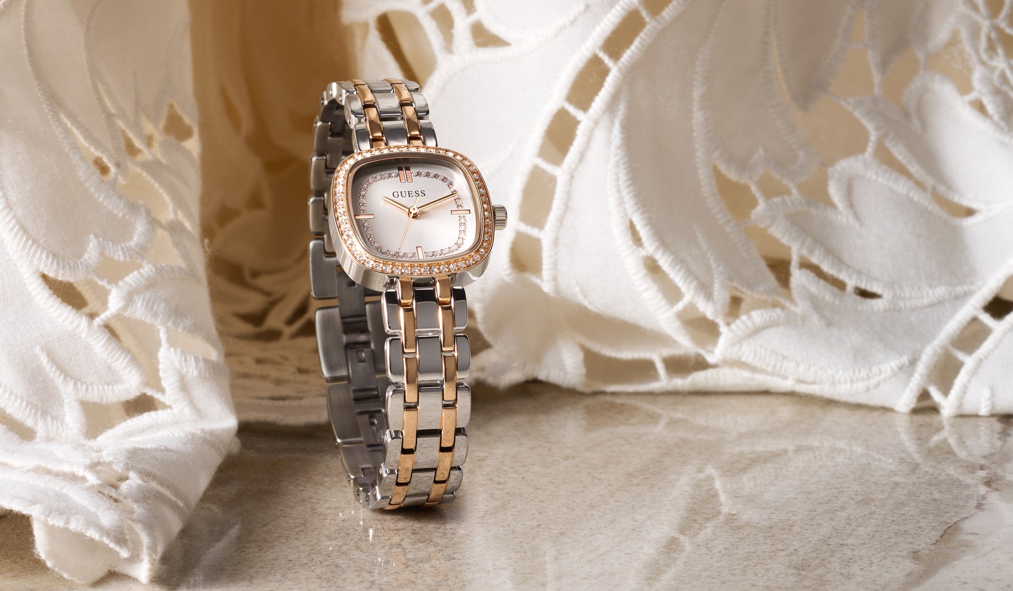 Two-tone watch on a textured surface with lace in the background GW1018L5