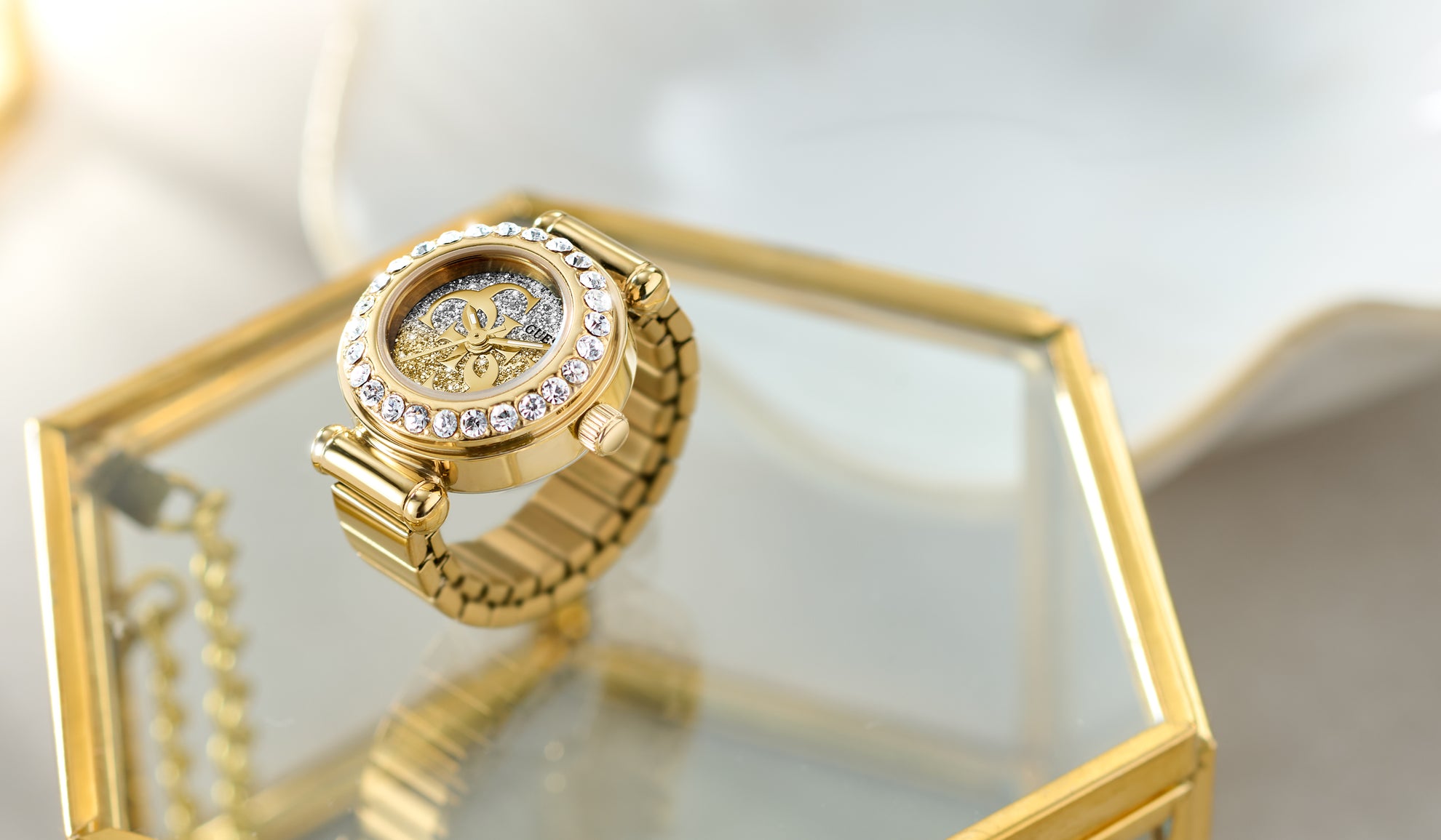 Gold watch ring with diamond accents on a reflective surface