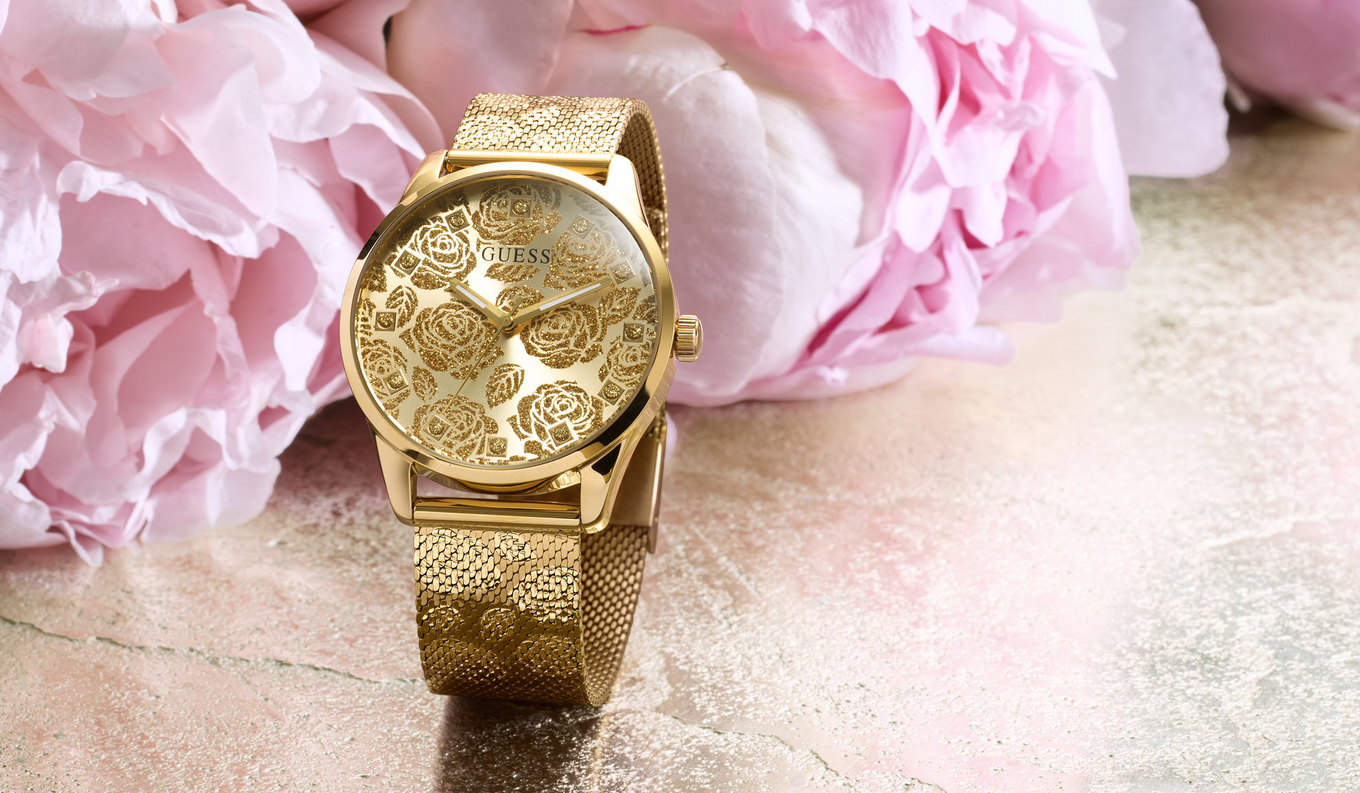 Gold watch with floral design on a pink floral background