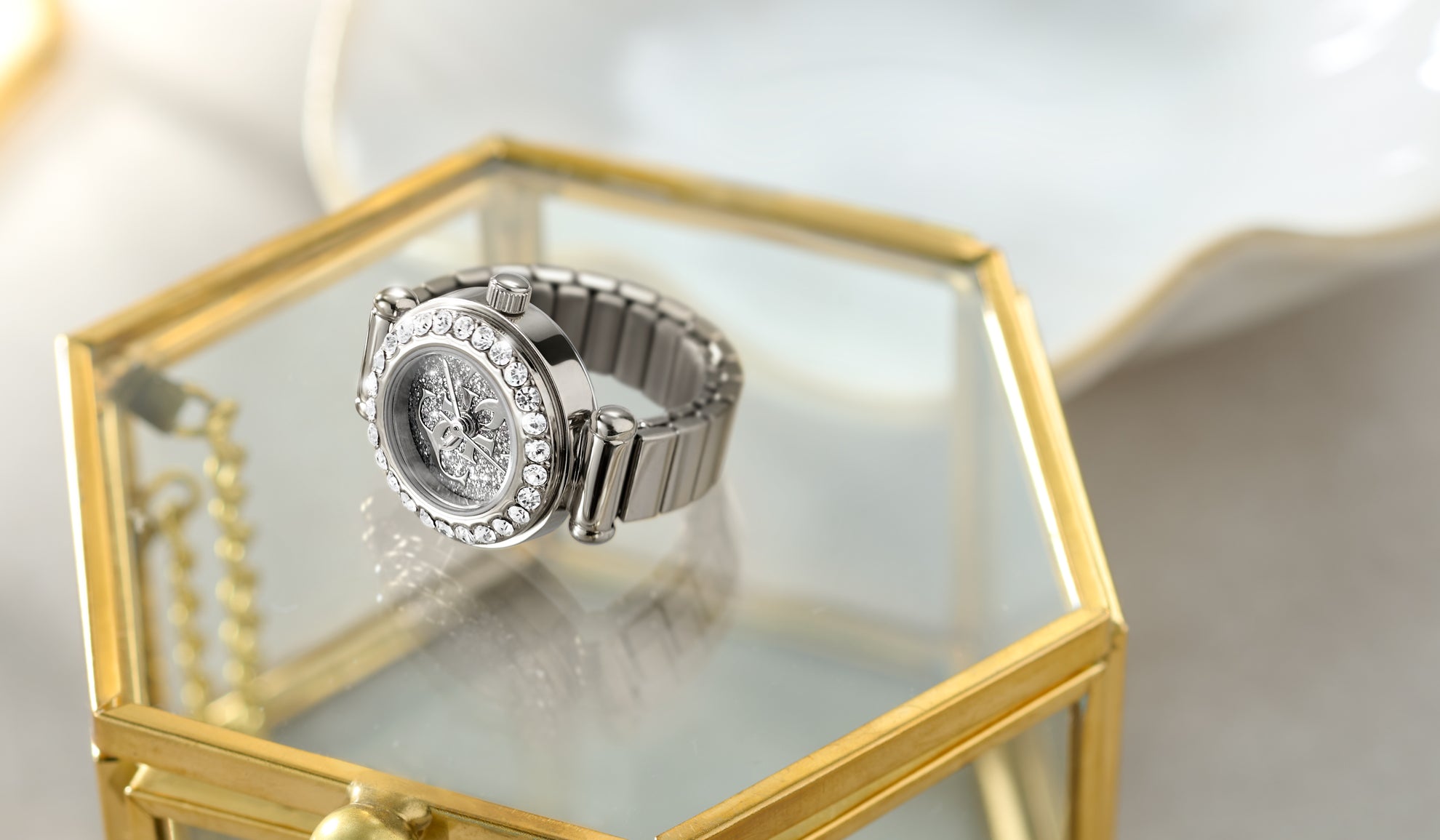 Silver watch ring with gemstones on a glass jewelry box