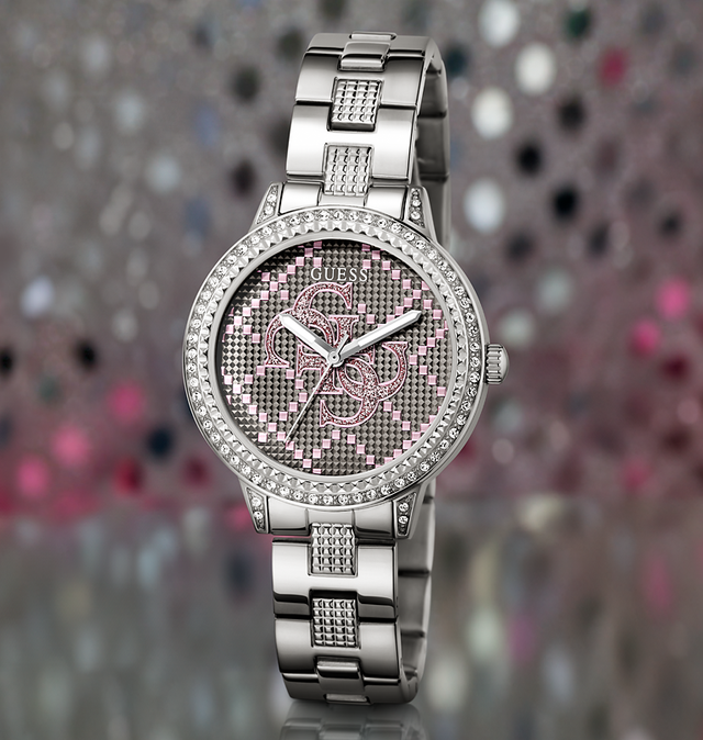 Silver Guess watch with pink face on a colorful blurred background
