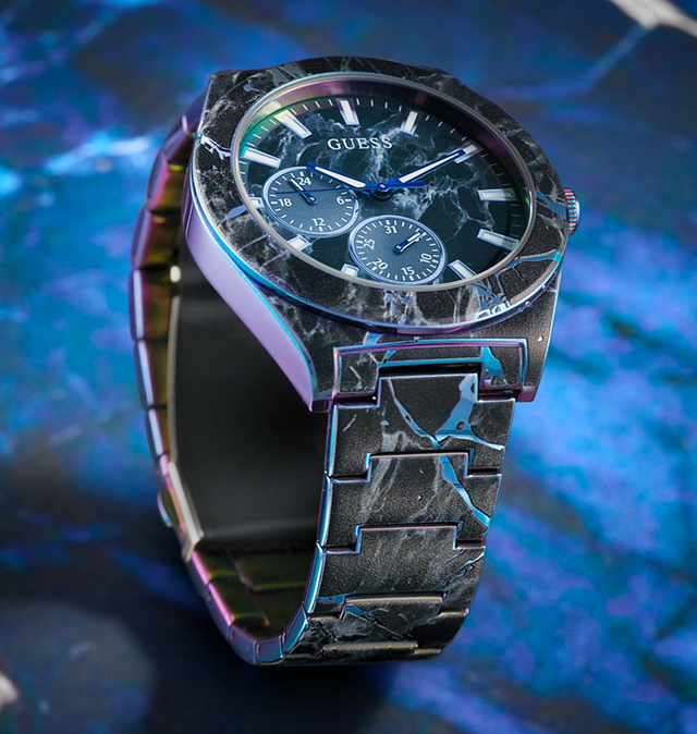 GUESS watch with a black marbled strap on a blue gradient background